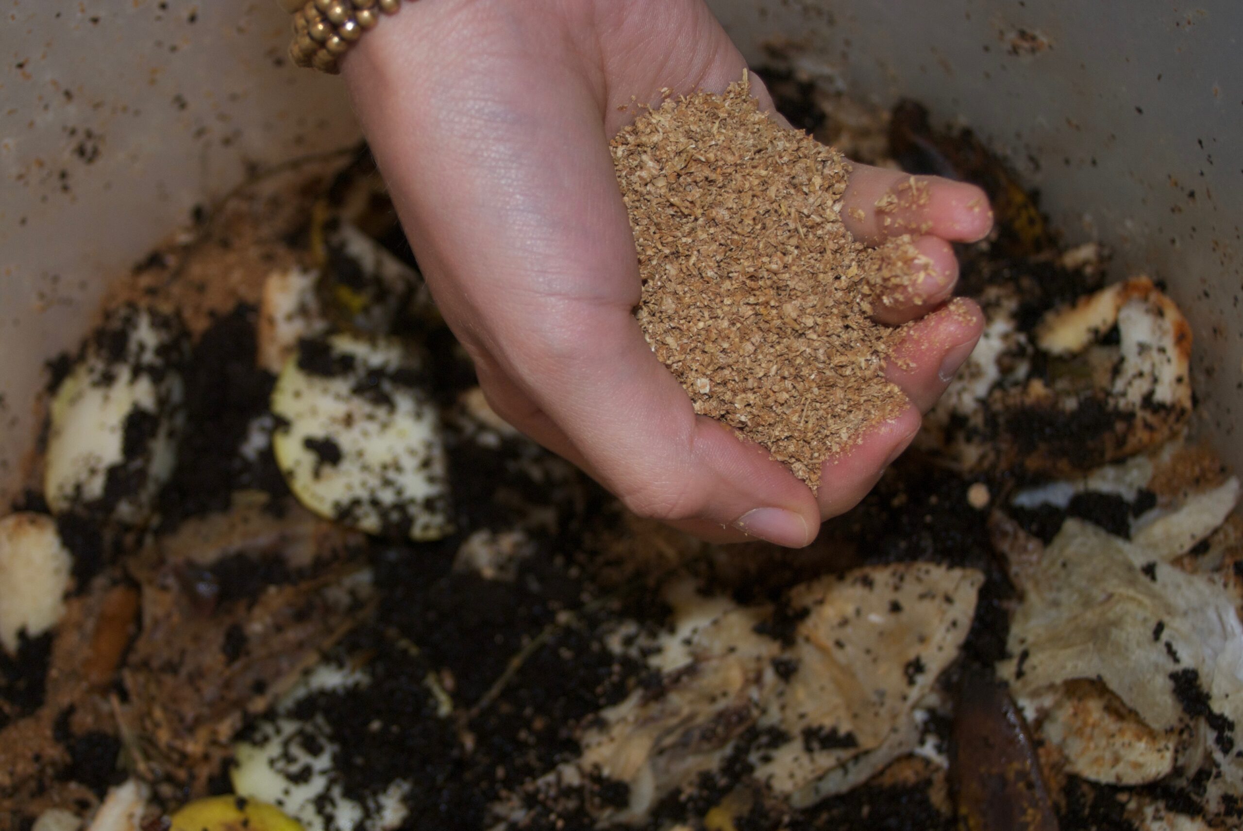 Earth Bokashi being sprinkled over food waste inside a Bokashi bin